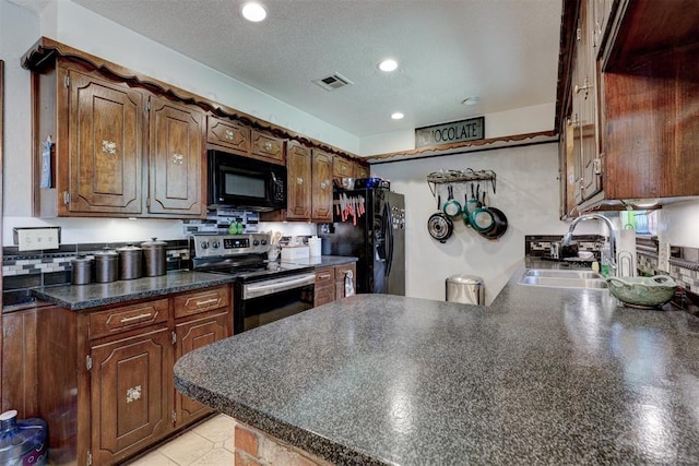801 Bonnie Ave, Purcell, OK 73080 - kitchen with black appliances, a sink, dark countertops, a peninsula, and recessed lighting