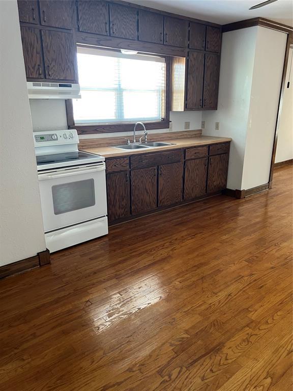 802 N Hudson St, Altus, OK 73521 - kitchen with electric stove, under cabinet range hood, dark wood-style floors, and light countertops