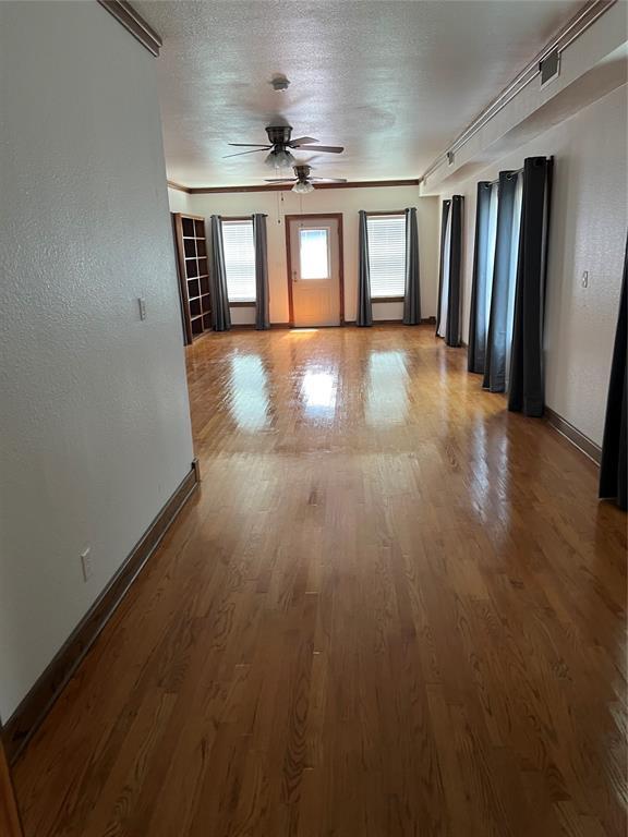 802 N Hudson St, Altus, OK 73521 - empty room featuring a ceiling fan, wood finished floors, and a textured ceiling