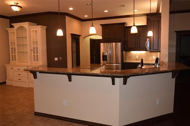 1713 Rain Tree Ln, Midwest City, OK 73130 - kitchen featuring stainless steel appliances, a breakfast bar, backsplash, crown molding, and dark stone countertops
