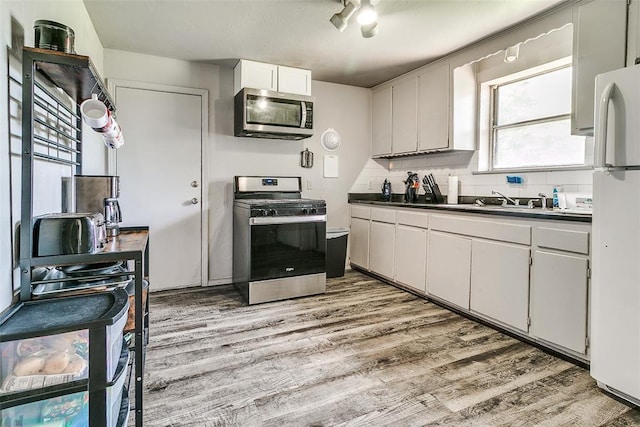 824 E Rose Dr, Midwest City, OK 73110 - kitchen featuring stainless steel appliances, light wood-style flooring, tasteful backsplash, and dark countertops