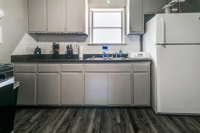 824 E Rose Dr, Midwest City, OK 73110 - kitchen with freestanding refrigerator, dark countertops, decorative backsplash, and dark wood-type flooring