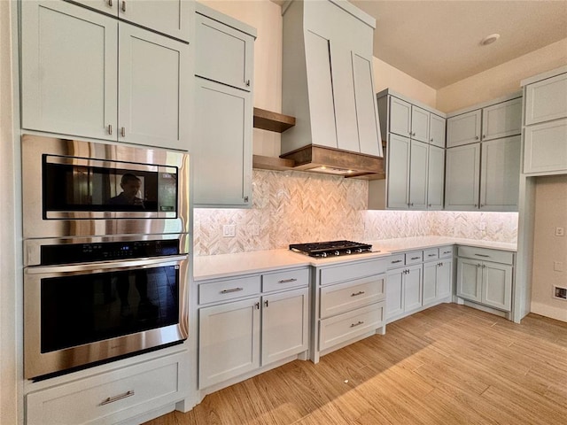 10165 NW 100th St, Yukon, OK 73099 - kitchen featuring stainless steel appliances, light countertops, light wood-style flooring, and tasteful backsplash
