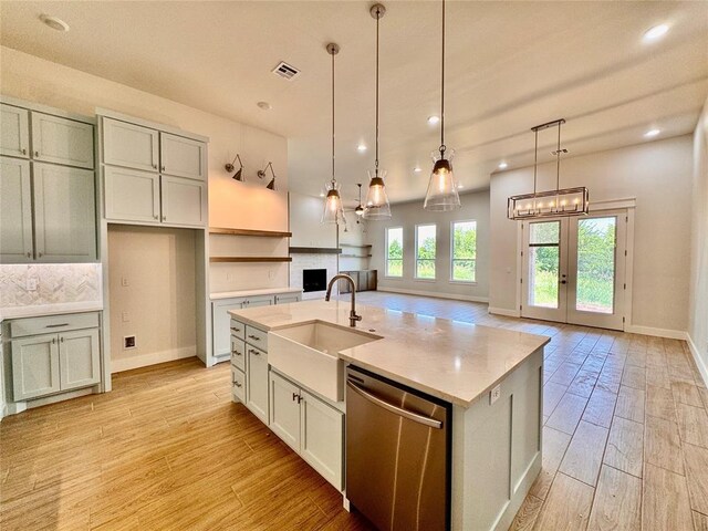 10165 NW 100th St, Yukon, OK 73099 - kitchen featuring dishwasher, light wood-style floors, a fireplace, an island with sink, and open floor plan