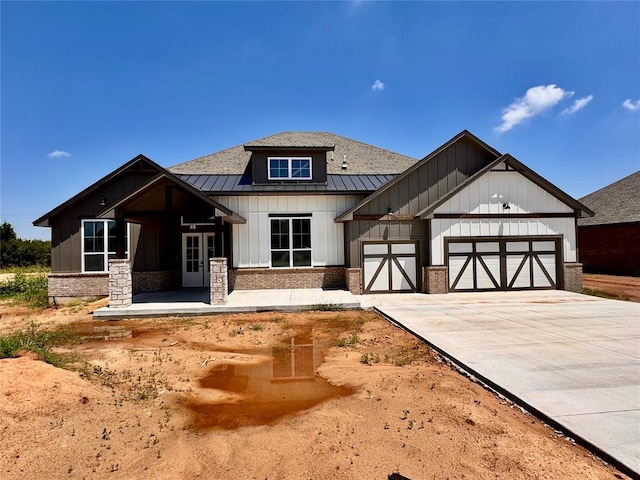 10165 NW 100th St, Yukon, OK 73099 - view of front of home featuring a standing seam roof, board and batten siding, concrete driveway, and a metal roof