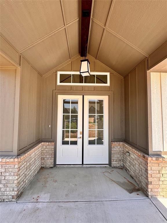 10165 NW 100th St, Yukon, OK 73099 - view of exterior entry with board and batten siding and french doors