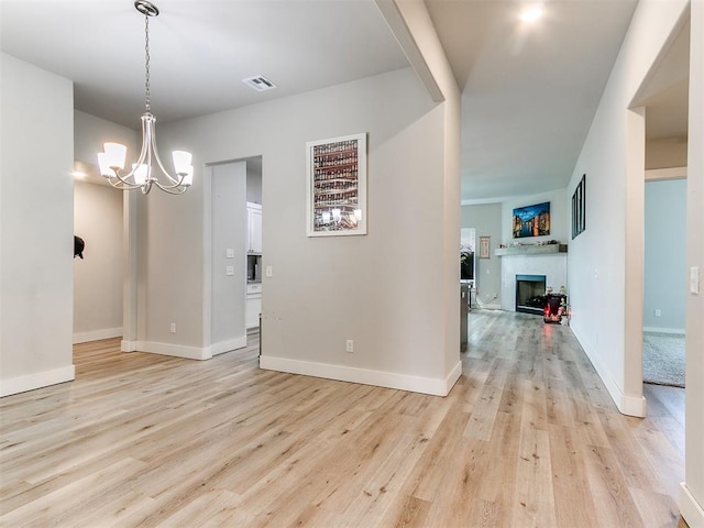 5512 Cheyenne Rd, Warr Acres, OK 73132 - unfurnished room with light wood-style flooring, a chandelier, and a fireplace