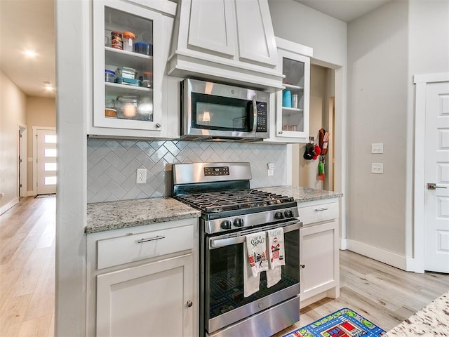 5512 Cheyenne Rd, Warr Acres, OK 73132 - kitchen featuring appliances with stainless steel finishes, decorative backsplash, light wood-type flooring, white cabinets, and light stone countertops
