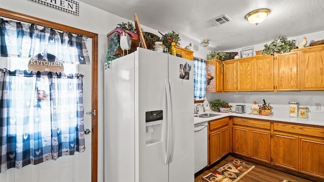 677 S Morgan Ave, Blanchard, OK 73010 - kitchen featuring white appliances, light countertops, a textured ceiling, brown cabinetry, and wood finished floors