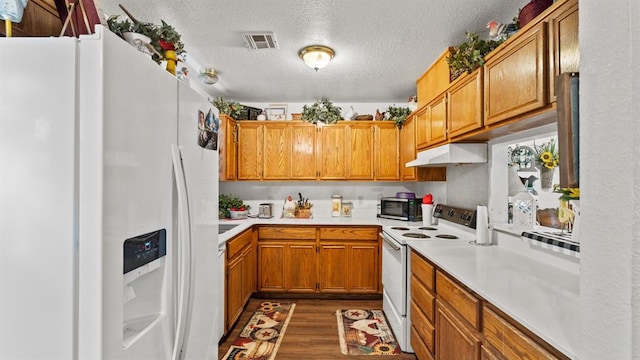 677 S Morgan Ave, Blanchard, OK 73010 - kitchen with white appliances, under cabinet range hood, brown cabinetry, dark wood-type flooring, and a textured ceiling