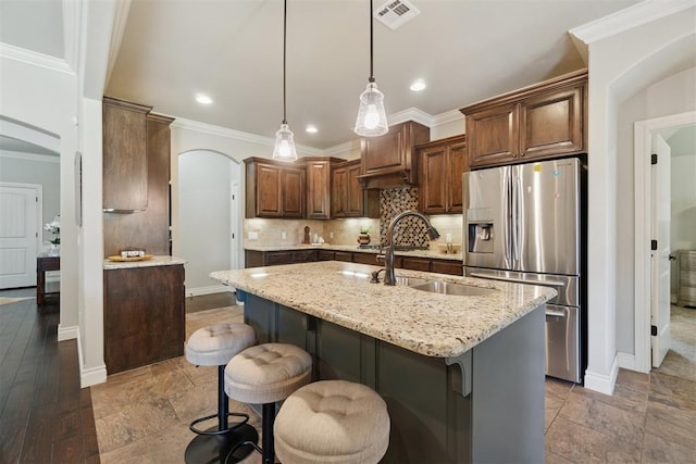 917 NW 186th St, Edmond, OK 73012 - kitchen with stainless steel refrigerator with ice dispenser, arched walkways, light stone countertops, an island with sink, and tasteful backsplash