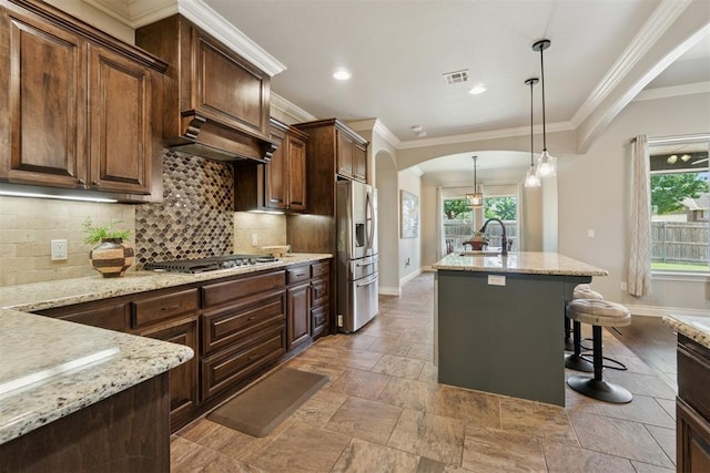 917 NW 186th St, Edmond, OK 73012 - kitchen featuring stainless steel appliances, arched walkways, healthy amount of natural light, decorative backsplash, and ornamental molding