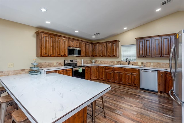 498 Big Horn Rd, Mcalester, OK 74501 - kitchen featuring stainless steel appliances, a peninsula, vaulted ceiling, a breakfast bar area, and dark wood-type flooring