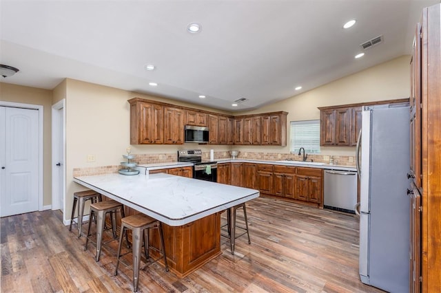498 Big Horn Rd, Mcalester, OK 74501 - kitchen with appliances with stainless steel finishes, a peninsula, a kitchen bar, wood finished floors, and vaulted ceiling