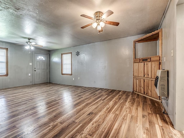 211 S 6th St, Mcloud, OK 74851 - unfurnished living room with ceiling fan, heating unit, light wood-style flooring, and a textured ceiling