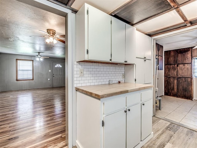 211 S 6th St, Mcloud, OK 74851 - kitchen featuring light wood-style floors, ceiling fan, wooden walls, white cabinetry, and decorative backsplash