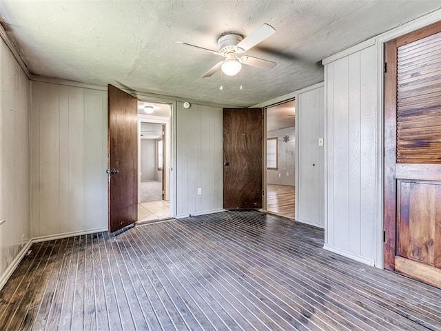 211 S 6th St, Mcloud, OK 74851 - unfurnished bedroom with wood-type flooring, wood walls, baseboards, and a ceiling fan