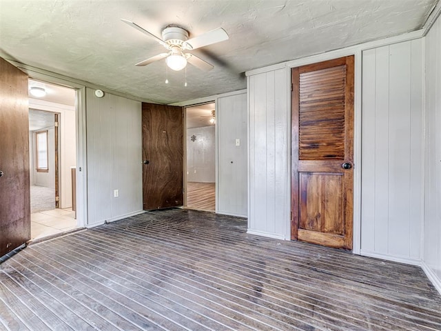 211 S 6th St, Mcloud, OK 74851 - unfurnished bedroom featuring wood finished floors, ceiling fan, wooden walls, and baseboards