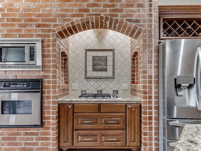1316 NW 171st St, Edmond, OK 73012 - kitchen featuring appliances with stainless steel finishes, brown cabinets, and light stone counters