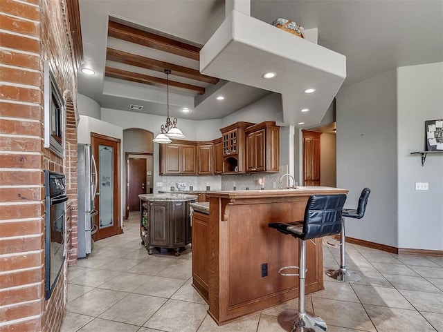 1316 NW 171st St, Edmond, OK 73012 - kitchen with light tile patterned flooring, a kitchen breakfast bar, stainless steel appliances, decorative backsplash, and recessed lighting
