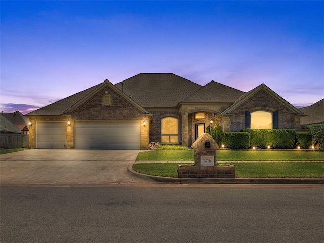 1316 NW 171st St, Edmond, OK 73012 - french provincial home featuring an attached garage, driveway, a front yard, brick siding, and a shingled roof