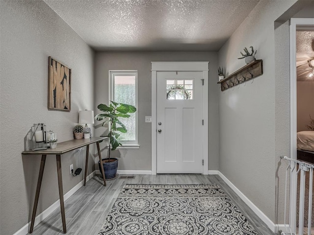 6513 NW 95th St, Oklahoma City, OK 73162 - foyer entrance with a textured ceiling, light wood-style flooring, baseboards, and a textured wall