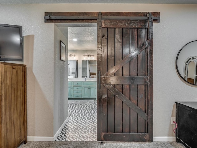 6513 NW 95th St, Oklahoma City, OK 73162 - hall featuring a barn door, a textured wall, and baseboards