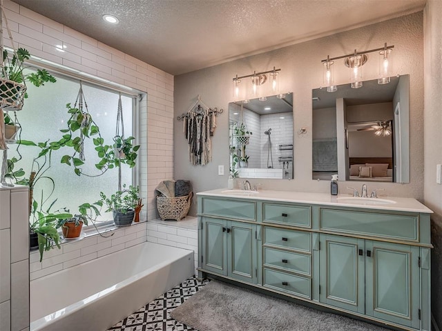 6513 NW 95th St, Oklahoma City, OK 73162 - full bath with double vanity, a textured ceiling, a bath, and ceiling fan