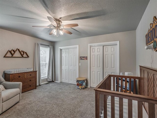 6513 NW 95th St, Oklahoma City, OK 73162 - carpeted bedroom featuring two closets, a textured ceiling, a ceiling fan, and a crib