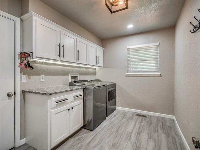 6513 NW 95th St, Oklahoma City, OK 73162 - laundry room with cabinet space, washer and clothes dryer, baseboards, a textured ceiling, and light wood-style floors