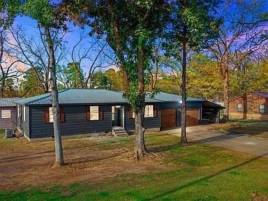 309 E Memorial St, Broken Bow, OK 74728 - view of front of home featuring concrete driveway, metal roof, and central AC