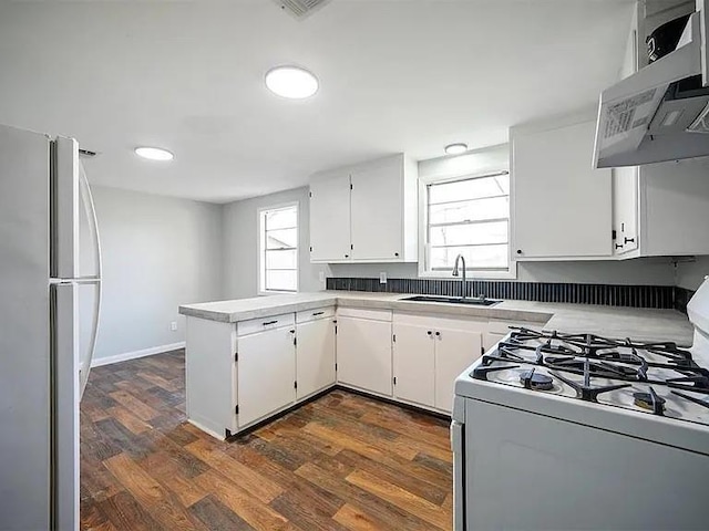 309 E Memorial St, Broken Bow, OK 74728 - kitchen featuring white range with gas stovetop, freestanding refrigerator, wall chimney range hood, a peninsula, and a sink