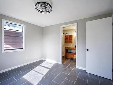 309 E Memorial St, Broken Bow, OK 74728 - unfurnished bedroom featuring baseboards and connected bathroom
