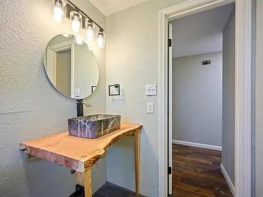 309 E Memorial St, Broken Bow, OK 74728 - bathroom featuring a textured wall, wood finished floors, a sink, and baseboards