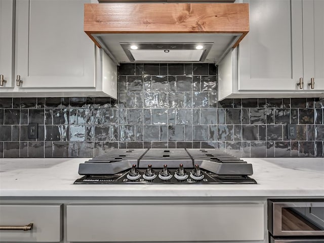 16101 S Rock Creek Rd, Shawnee, OK 74801 - kitchen with black gas stovetop, white cabinets, tasteful backsplash, and range hood