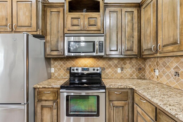 2913 Elmo Way, Oklahoma City, OK 73160 - kitchen with appliances with stainless steel finishes, decorative backsplash, and light stone counters