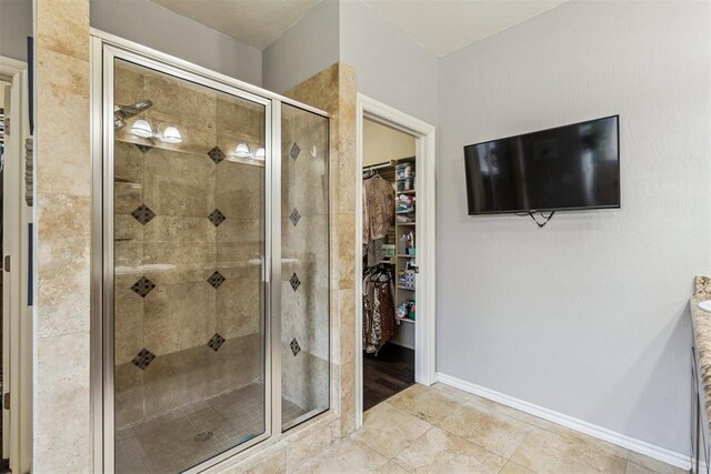 2913 Elmo Way, Oklahoma City, OK 73160 - bathroom featuring a stall shower, a spacious closet, and baseboards