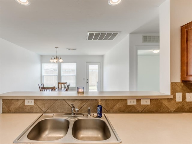 724 Ga Zump Dr, Norman, OK 73069 - kitchen with a sink, light countertops, backsplash, and a chandelier