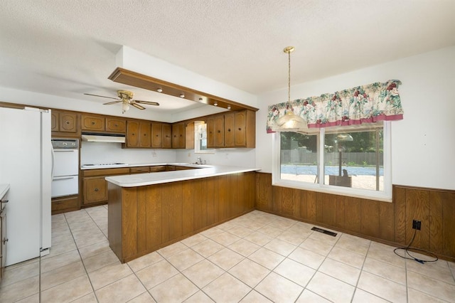 3860 Wake Forest Rd, Edmond, OK 73034 - kitchen with freestanding refrigerator, under cabinet range hood, a peninsula, stovetop, and light countertops