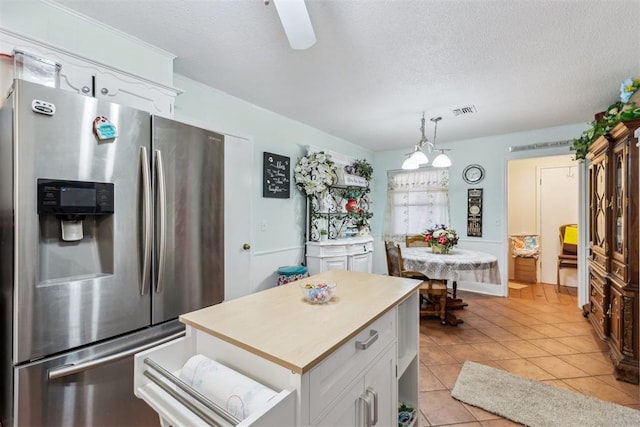 4912 NW 29th St, Oklahoma City, OK 73127 - kitchen featuring stainless steel fridge, white cabinets, a textured ceiling, light tile patterned floors, and light countertops
