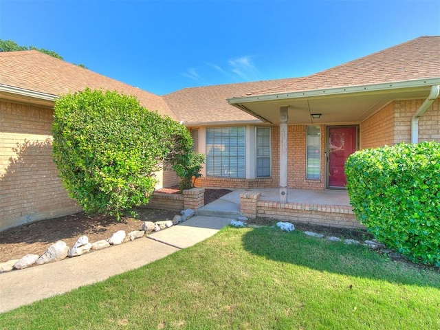 5201 SE 53rd St, Oklahoma City, OK 73135 - entrance to property featuring brick siding, a lawn, roof with shingles, and a porch