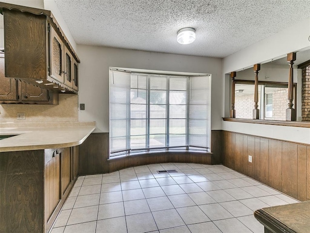 5201 SE 53rd St, Oklahoma City, OK 73135 - unfurnished dining area with a wainscoted wall, a textured ceiling, wooden walls, and light tile patterned floors
