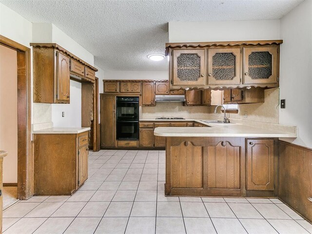 5201 SE 53rd St, Oklahoma City, OK 73135 - kitchen featuring a sink, a peninsula, under cabinet range hood, light countertops, and light tile patterned flooring
