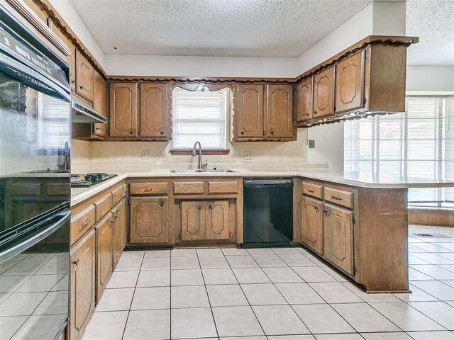 5201 SE 53rd St, Oklahoma City, OK 73135 - kitchen featuring black appliances, a sink, a peninsula, a textured ceiling, and healthy amount of natural light