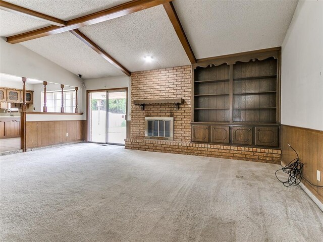 5201 SE 53rd St, Oklahoma City, OK 73135 - unfurnished living room with a textured ceiling, wood walls, wainscoting, built in shelves, and a brick fireplace