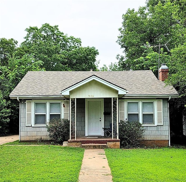 926 S 9th St, Chickasha, OK 73018 - view of front of house with a chimney, a front lawn, roof with shingles, and a porch