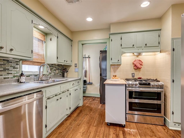 1616 NW 41st St, Oklahoma City, OK 73118 - kitchen with appliances with stainless steel finishes, a sink, tasteful backsplash, light wood-style floors, and recessed lighting