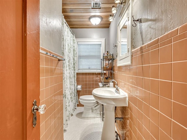 1616 NW 41st St, Oklahoma City, OK 73118 - bathroom with tile walls, toilet, tile patterned floors, wooden ceiling, and a shower with curtain