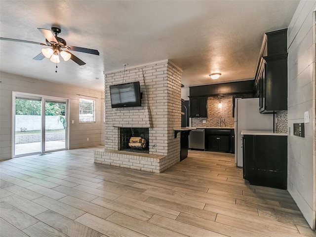 1117 Washington St, Edmond, OK 73034 - kitchen with dark cabinetry, stainless steel dishwasher, a ceiling fan, open floor plan, and tasteful backsplash