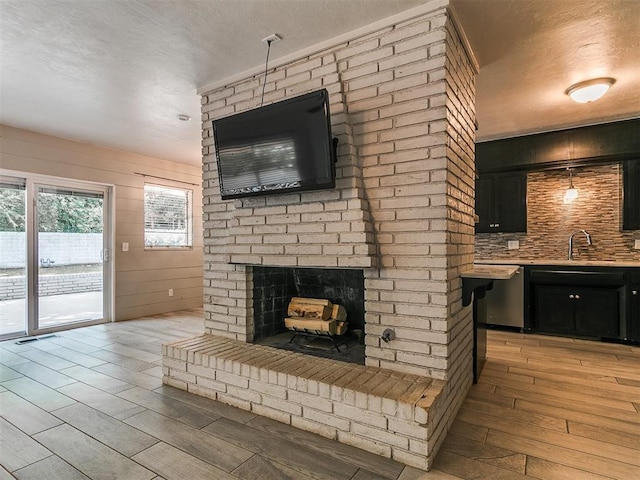 1117 Washington St, Edmond, OK 73034 - unfurnished living room with light wood finished floors, a brick fireplace, and a textured ceiling